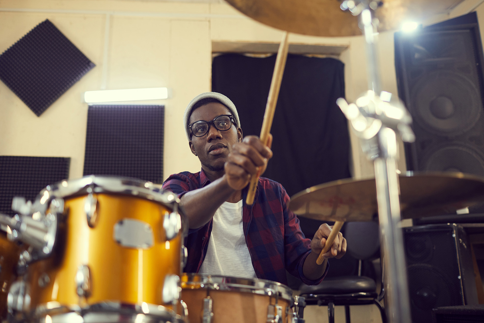 Portrait of young African-American drummer preparing for concert or rehearsal during sound check, copy space